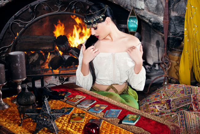 Обои картинки фото девушки, rivi madison, брюнетка, украшения, блузка, камин, огонь, стол, карты