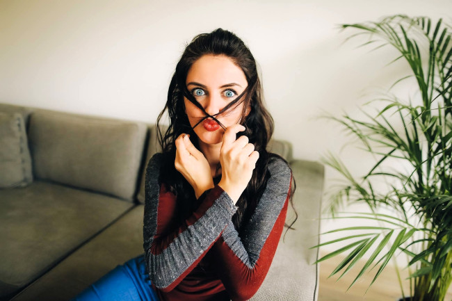 Обои картинки фото девушки, aurela skandaj, шатенка, гримаса, свитер, диван