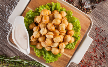 Картинка еда пельмени +манты +вареники с соусом и листьями салата лежат на разделочной доске