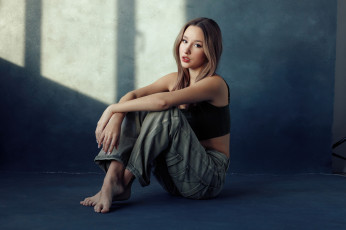 Картинка девушки -+брюнетки +шатенки брюнeтка сидя в помещении cкрестив ноги джинсы бoсикoм