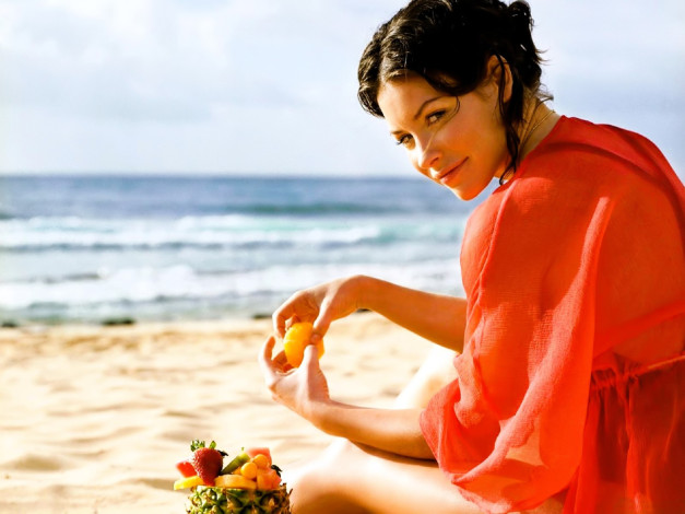 Обои картинки фото девушки, evangeline lilly, шатенка, туника, фрукты, море, пляж, песок