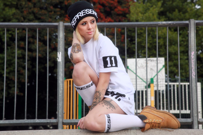 Обои картинки фото девушки, alysha nett, блондинка, шапка, футболка, гольфы, ботинки, забор