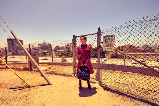 Обои картинки фото девушки, olivia holt, плащ, сумка, забор, город