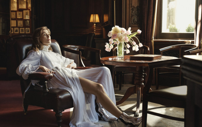 Обои картинки фото девушки, rosamund pike, окно, цветы, стол, кресло, платье, блондинка