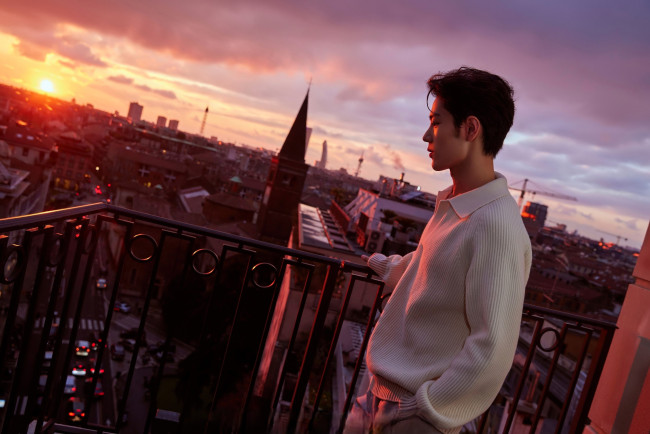 Обои картинки фото мужчины, xiao zhan, актер, свитер, балкон, город, панорама, закат