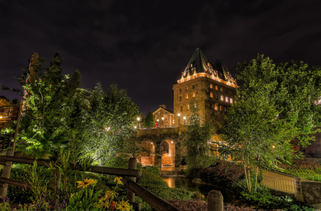 Обои картинки фото epcot`s canada, города, диснейленд, дома, арки, деревья, фонари, мост, река, ночь