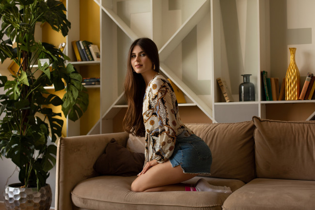 Обои картинки фото девушки, - брюнетки,  шатенки, модель, damp, zergut, luna, pica, брюнетка, джинсовые, шорты, диван, носки, короткие, растения, блузка, белые, ноги, вместе, на, коленях, длинные, рукава, волосы, помада