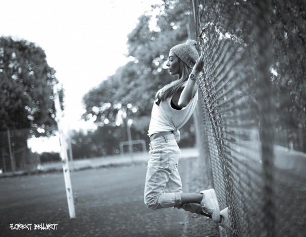 Обои картинки фото девушки, -unsort , Черно-белые обои, майка, забор, сетка, блондинка, джинсы, часы, шапка